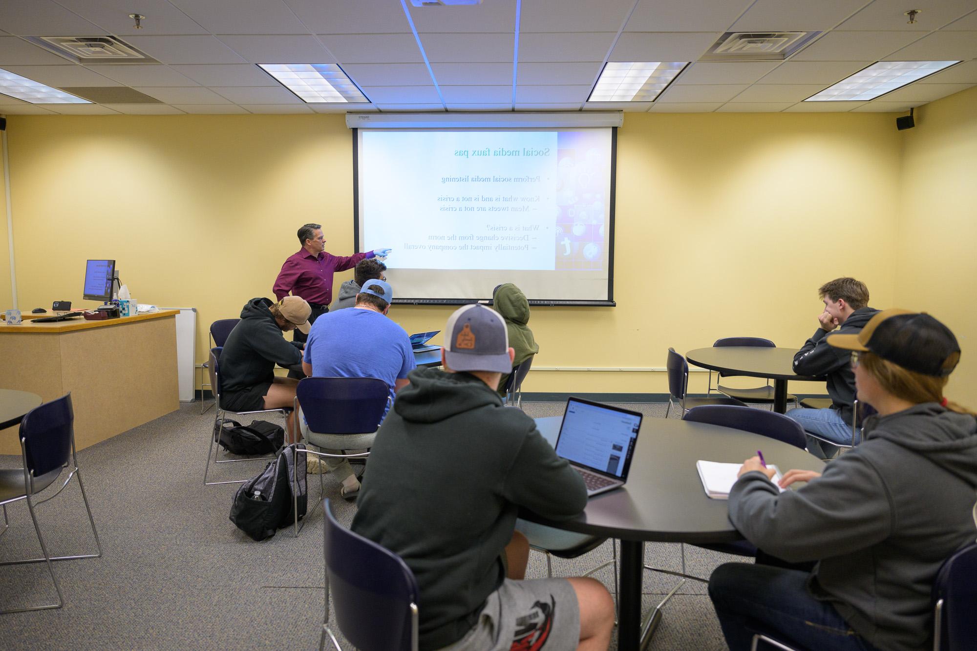 Male instructor showing students an image projected on a screen